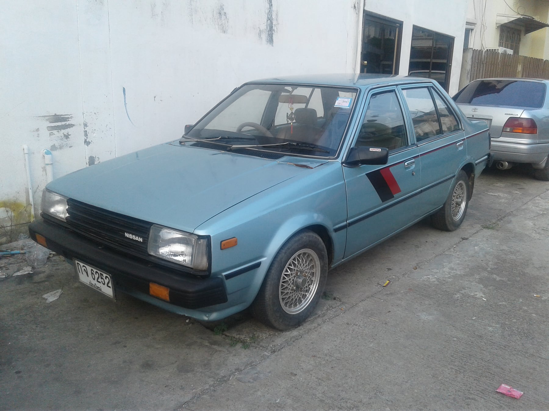 Exact 1982-1983 B11 sedan and 1.5-litre family; Thai GL trim, market, transmission, wheels and side graphics are representative rather than exact SGL Extra evidence.