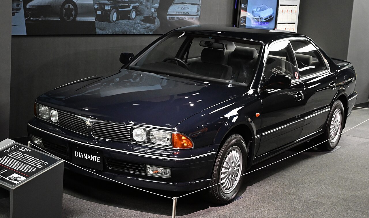 Representative first-generation Mitsubishi Diamante 25E-SE at a museum, photographed in 2026; not the profiled 1990 25V. Build year and exact mechanical specification unverified.