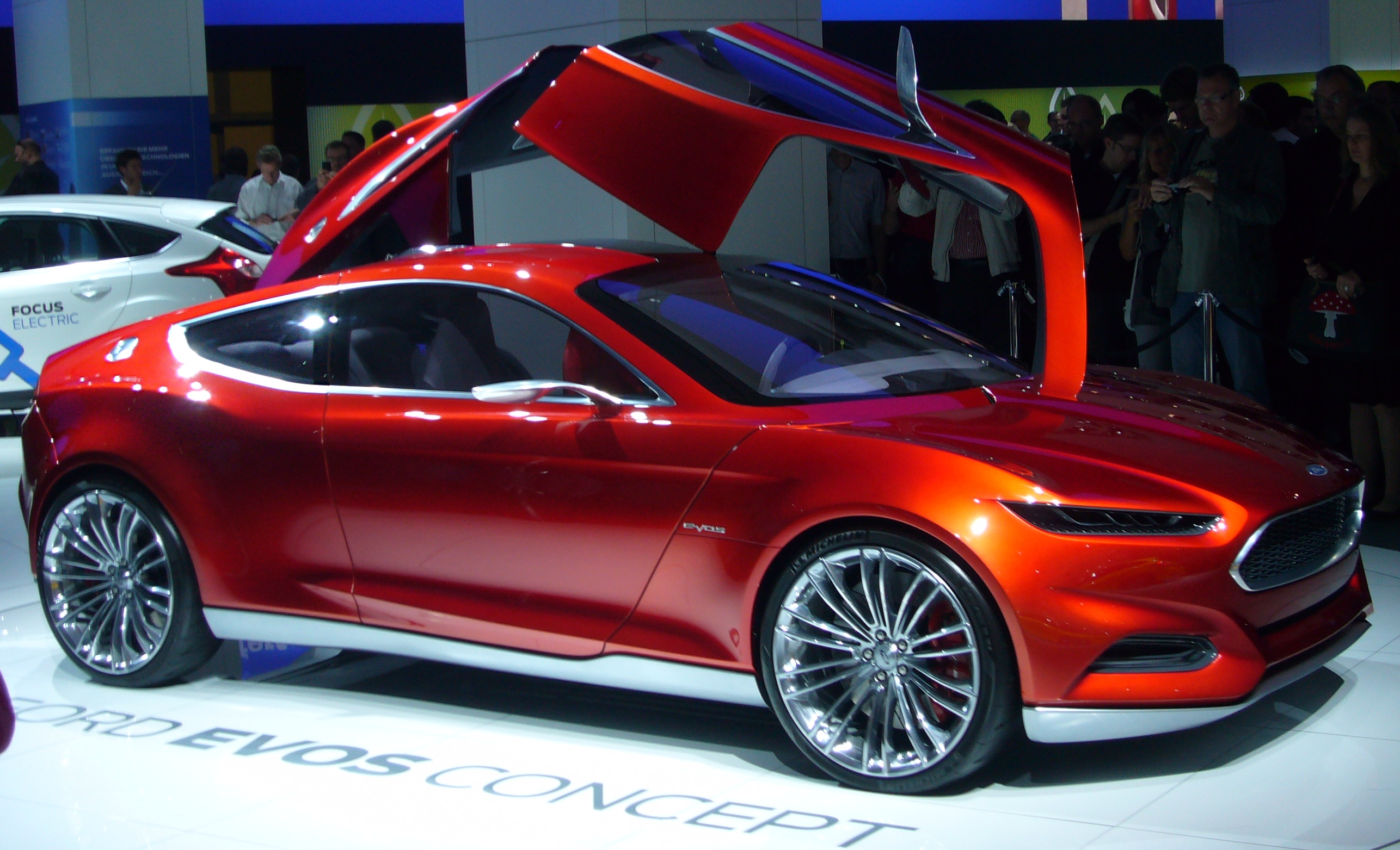Exact physical 2011 Frankfurt Evos concept in metallic red/copper with all four opposing doors raised; not the unrelated 2021 China-market EVOS.