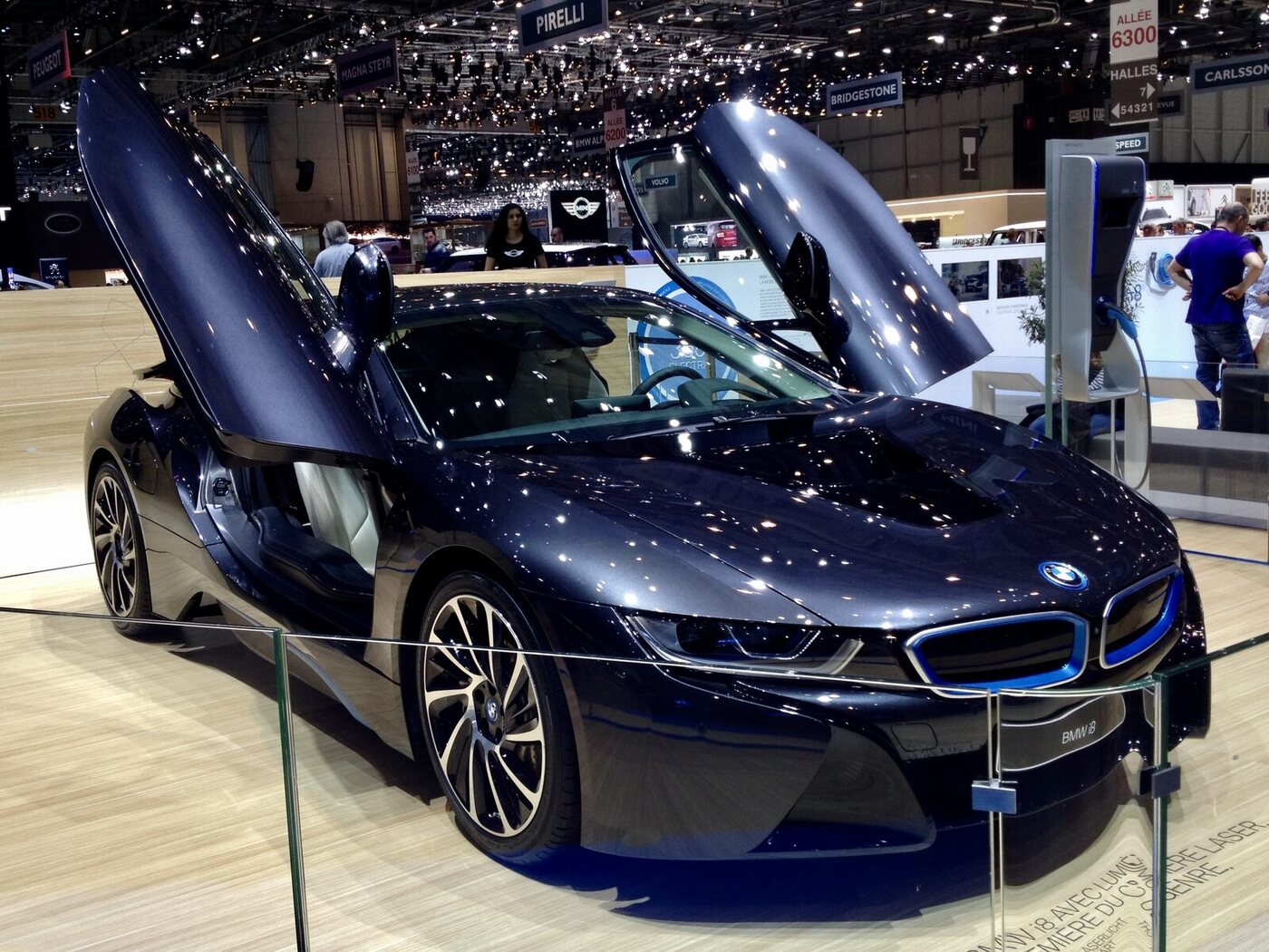 The photograph shows a production-form BMW i8 at the 2014 Geneva Motor Show, matching the profiled launch-year European coupé. It is a display car rather than an on-road test car.
