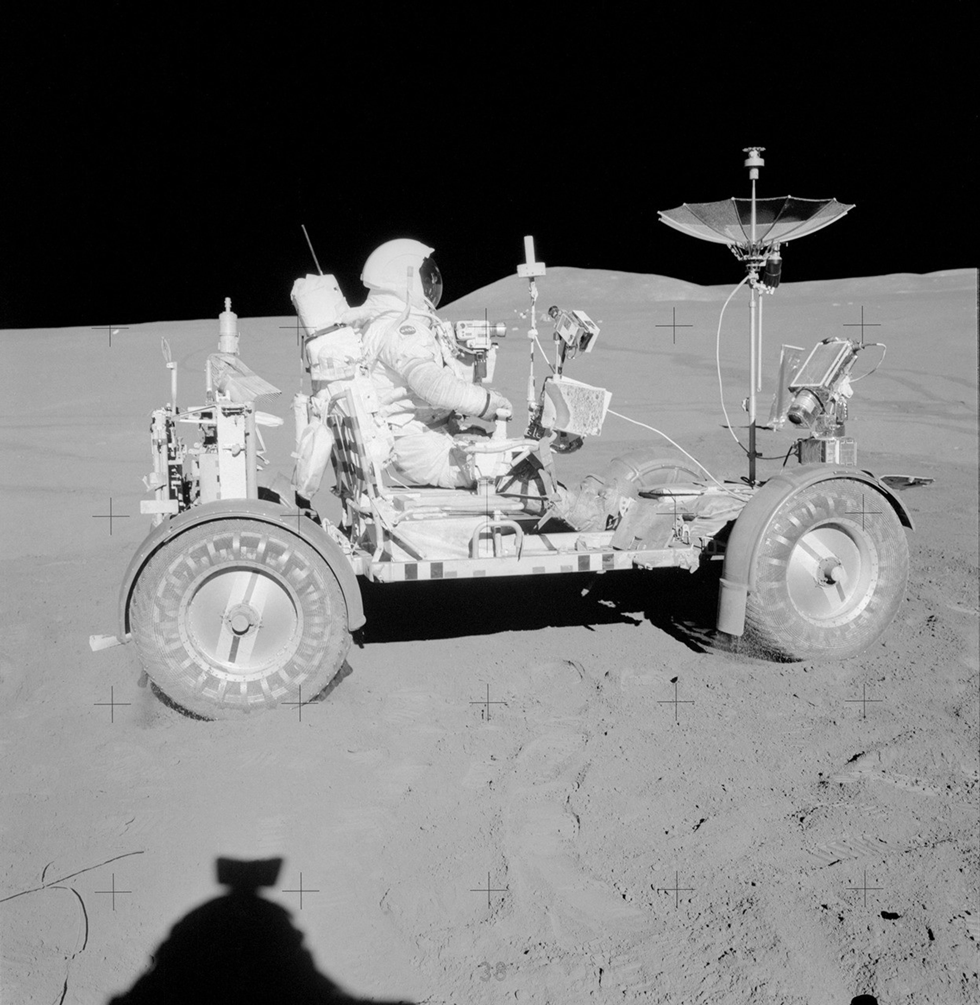 Apollo 15 commander David Scott in a white spacesuit seated in the actual Lunar Roving Vehicle on the Moon beside scientific equipment at Hadley-Apennine.