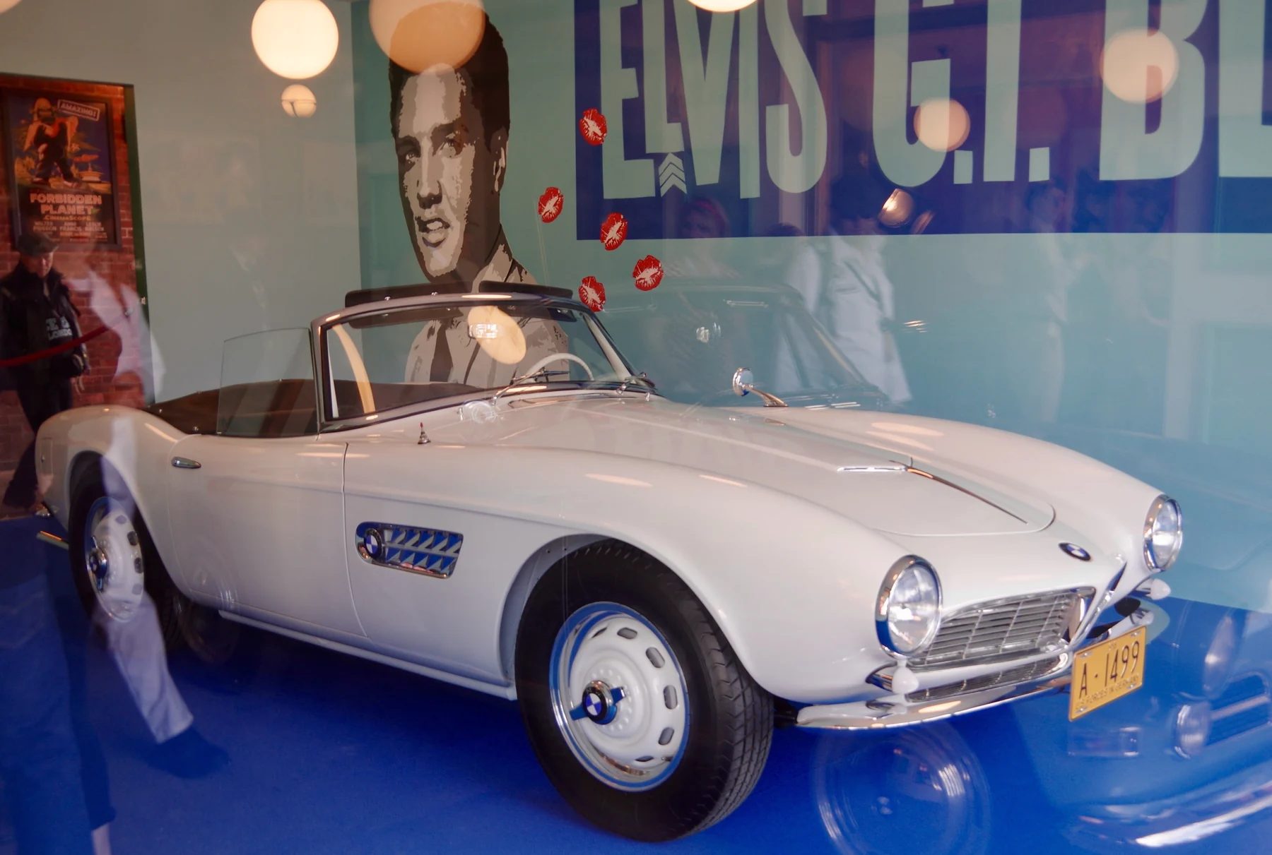 Elvis Presley’s restored white BMW 507 on display at Goodwood Revival, with an Elvis exhibit behind it.