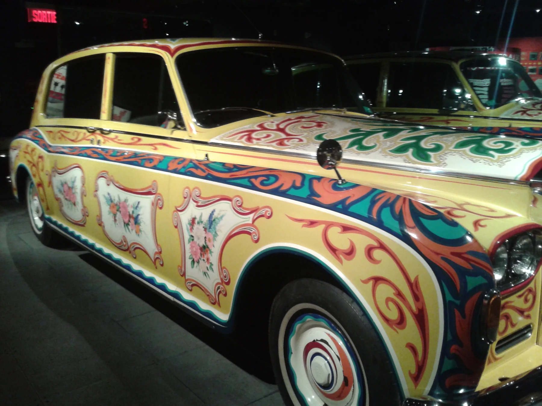 A side and front detail of John Lennon’s yellow psychedelic Rolls-Royce Phantom V in the Montréal museum exhibition.