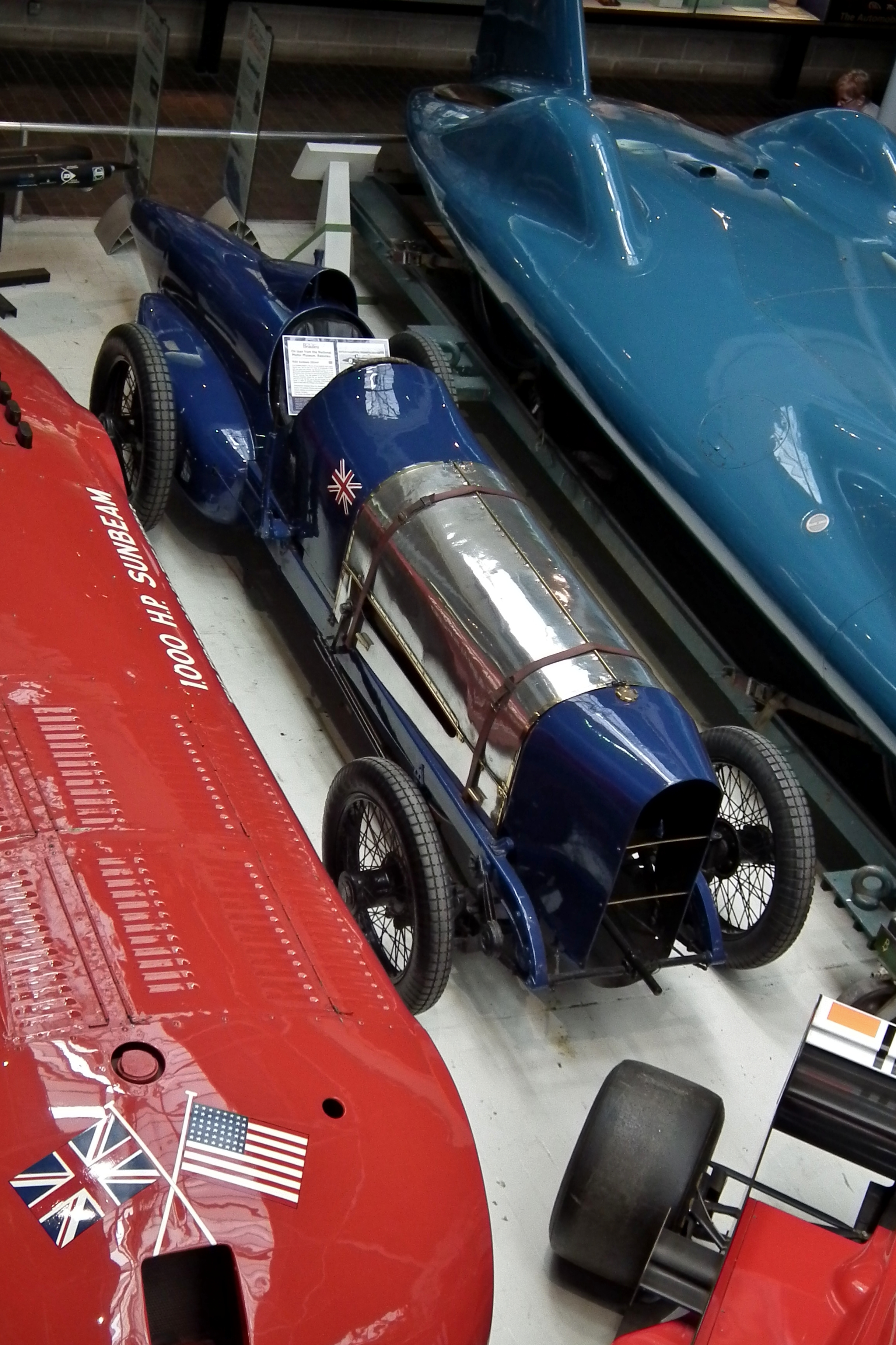The actual surviving dark-blue Sunbeam 350hp Blue Bird viewed from above in the National Motor Museum, between two other record cars.