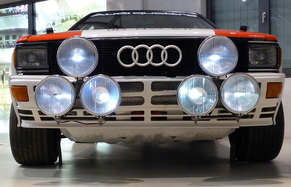Front view of the actual Mouton-associated 1983 Audi quattro A1 rally car at the Deutsches Technikmuseum, with six rally lamps and no registration visible.