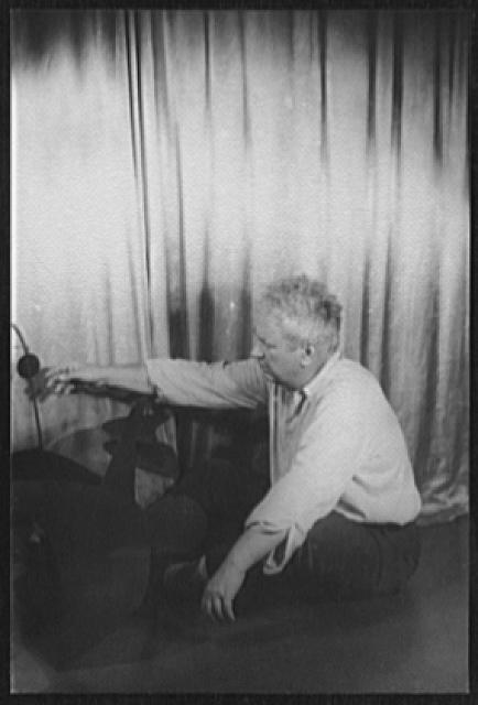 Alexander Calder seated beside one of his sculptures in Carl Van Vechten’s 1947 identification portrait.