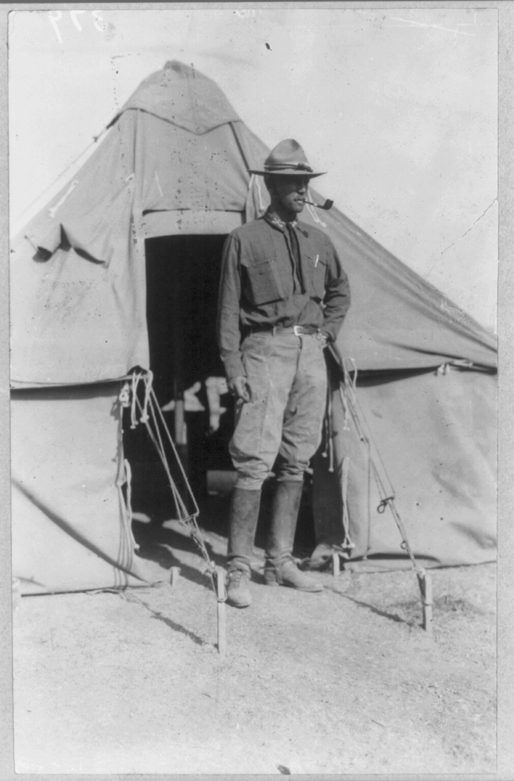 Full-length 1916 black-and-white portrait of Lt. George S. Patton in uniform standing outside a tent.