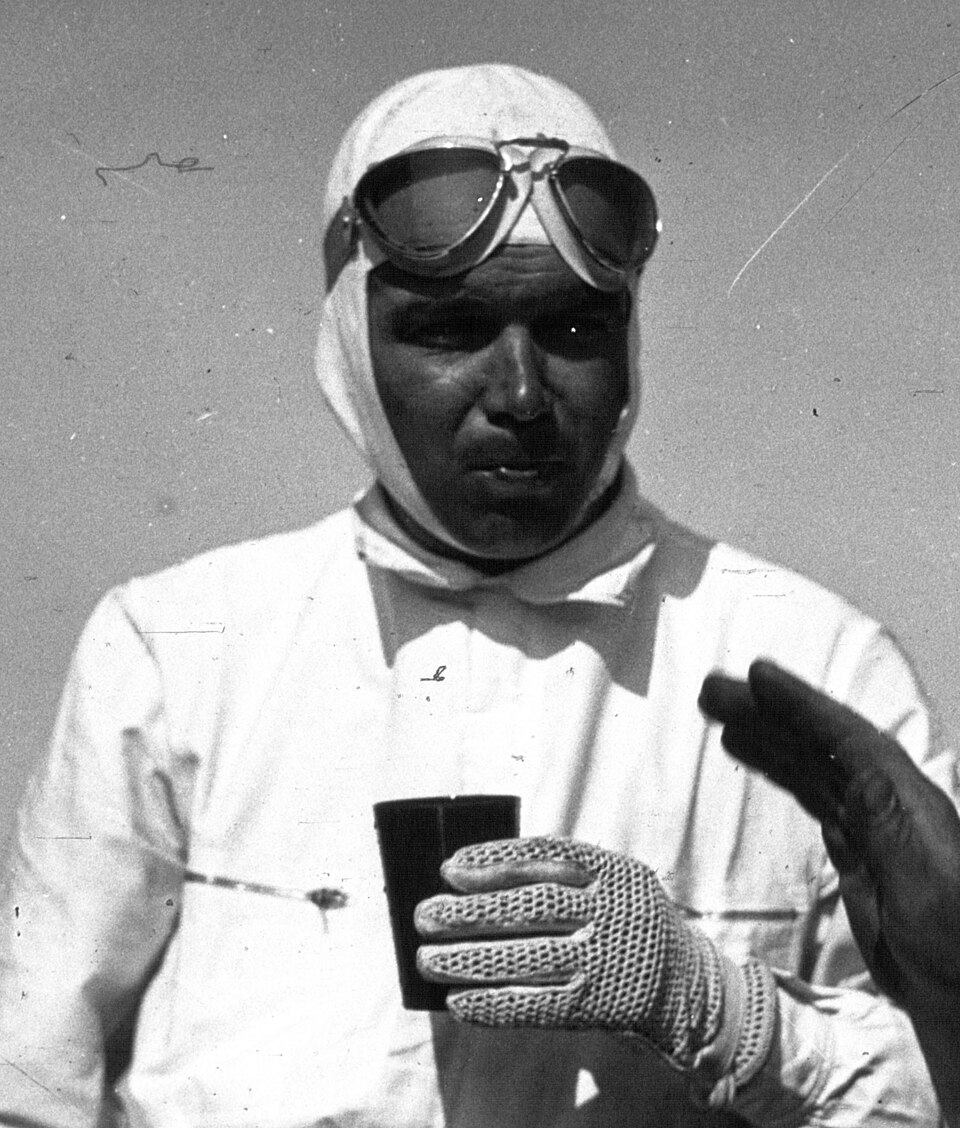 Black-and-white close portrait of Rudolf Caracciola wearing a racing cap and goggles at the 1935 French Grand Prix.