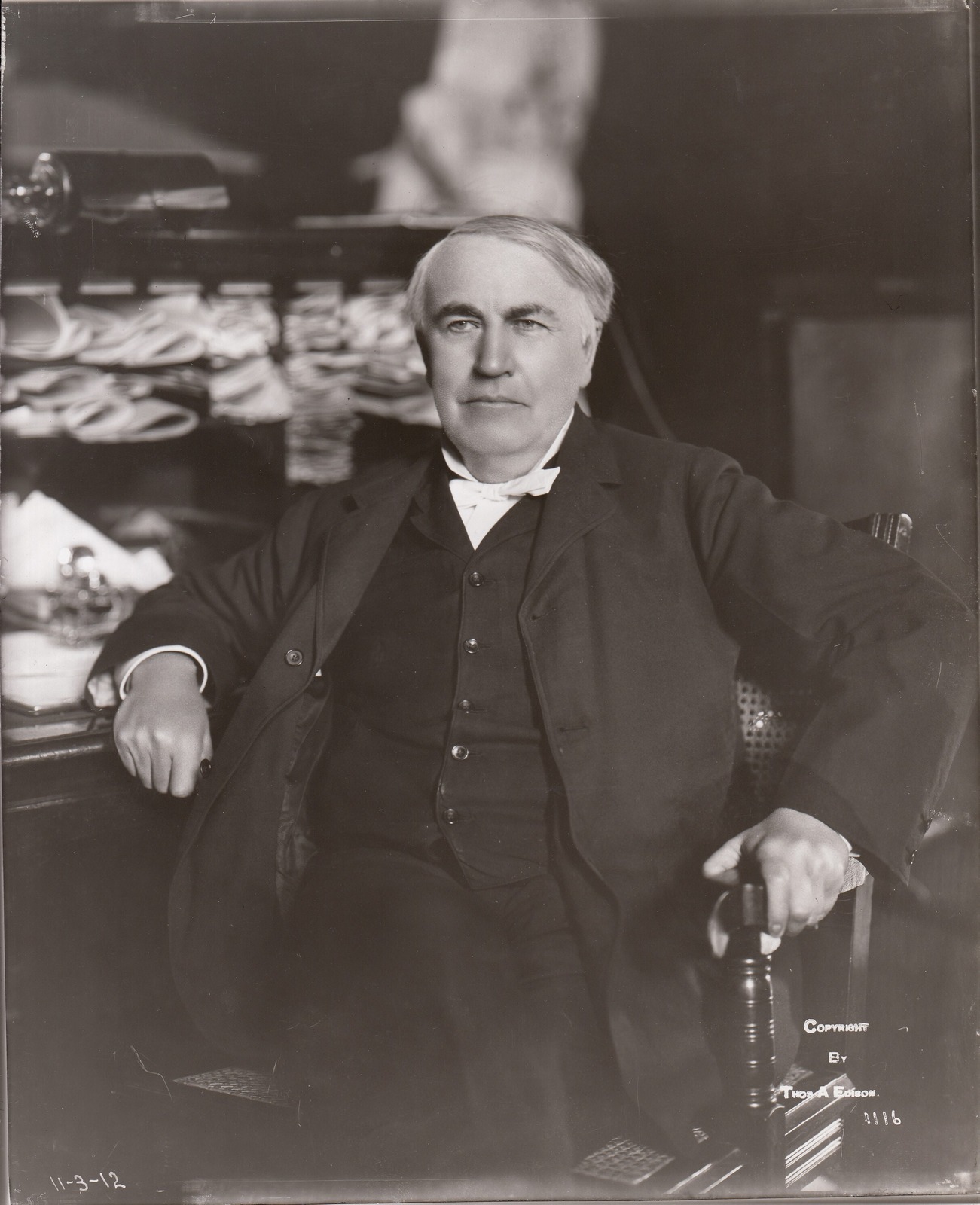 Black-and-white 1912 portrait of Thomas Edison seated at his desk in the West Orange Laboratory library.