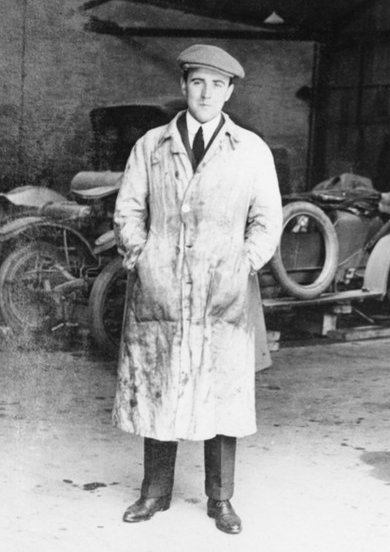 Black-and-white full-length portrait of W.O. Bentley in a light workshop coat and flat cap.