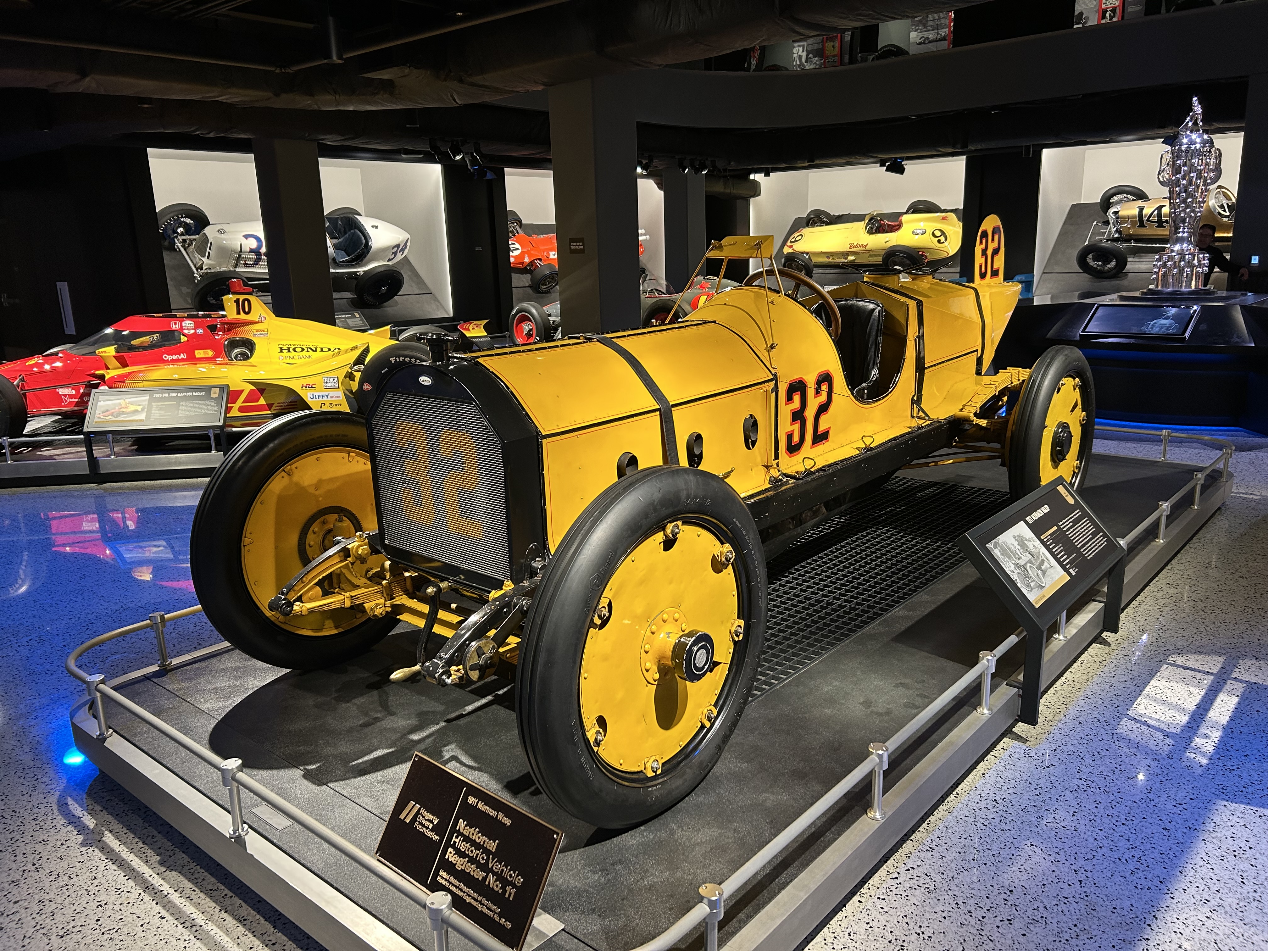 The actual yellow-and-black Marmon Wasp race car number 32 displayed at the Indianapolis Motor Speedway Museum, viewed from the front left.