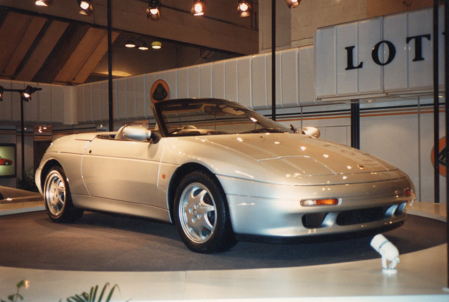 The Commons record identifies an exact 1989 Lotus Elan SE M100 photographed at the London Motorfair; the media researcher visually reviewed the complete launch-display car.